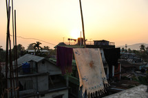 blanket drying on a clothesline above roofs 