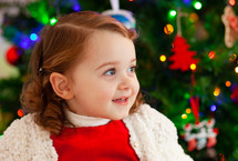Portrait of a little child with red dress near Christmas tree