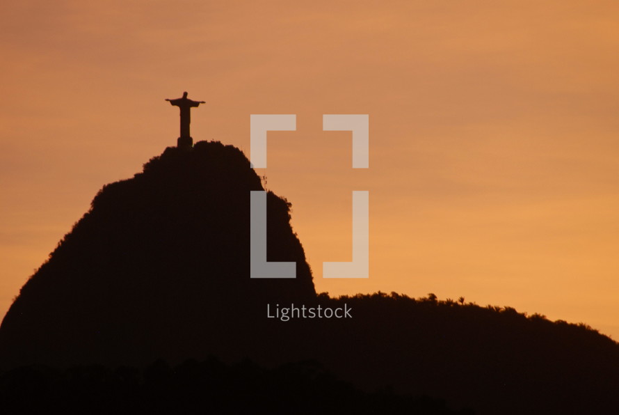 Jesus statue atop a hill at sunset