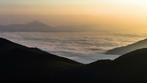 Sea of foggy clouds waves in mountains valley in sunny summer morning nature Time lapse
