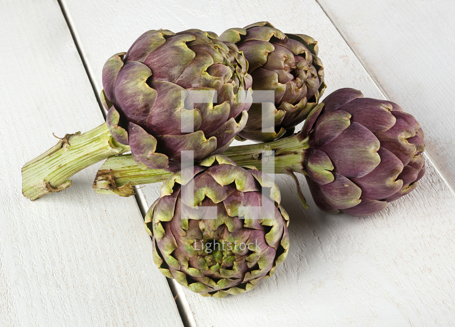 raw artichokes on white wooden table