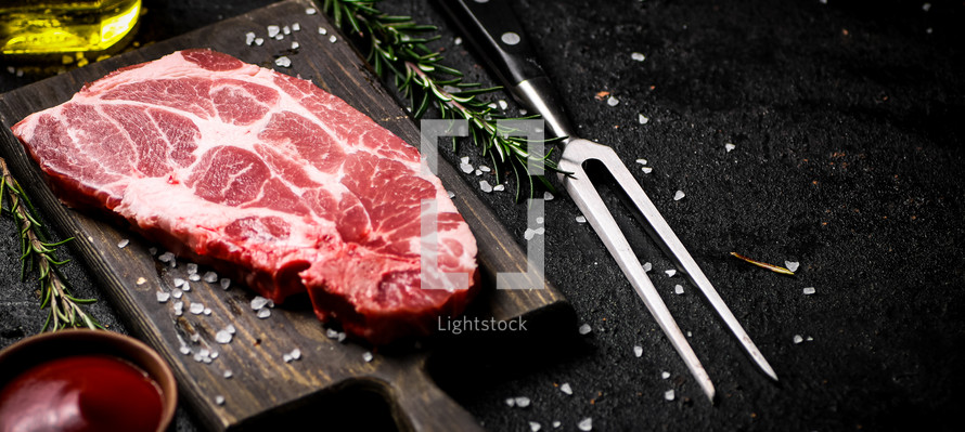 Raw pork steak on a stone board. On a black background. High quality photo