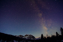 stars in the night sky over snowy mountain peaks 