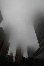 dense fog at the top of skyscrapers in a city 