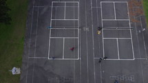 Four men playing pickle ball sports on an outdoor court during an overcast day
