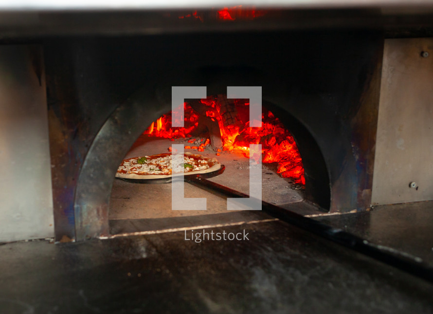 Cooking a margherita pizza in a wood oven.