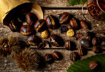 Roasted chestnuts in paper cone on wooden table