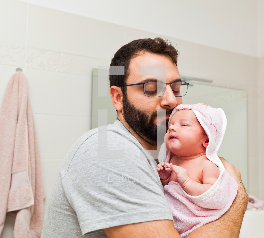 dad holds his daughter in his arms after the first bath