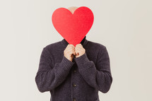 man holding a paper heart cutout 
