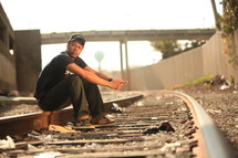 man sitting on railroad tracks