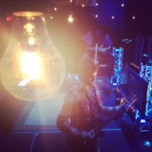 light bulb glowing over a musician playing a guitar on stage