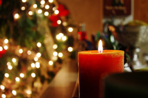 candle burning in front of a Christmas tree