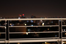 City lights in the background through a rail