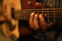 Man's fingers playing guitar