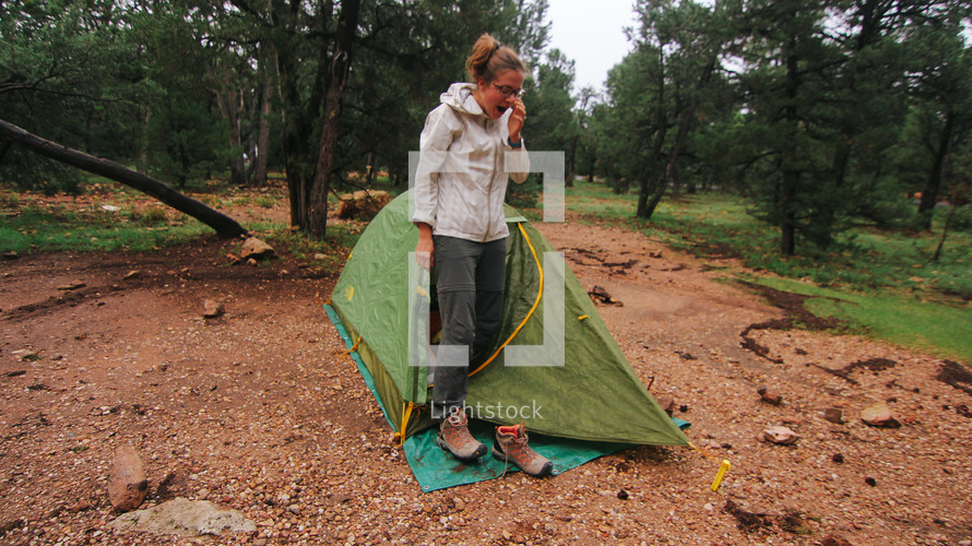 yawning woman setting up a tent 