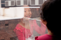 Asian girl child looking out a window smiling 