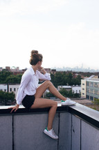 a woman sitting on a balcony railing looking out at the view 