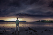 man standing on a shore at sunset 