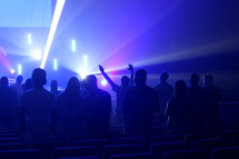 hands raised under lights at a worship service 