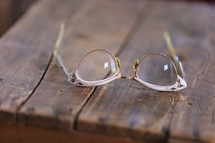 Cat eye glasses laying on a rugged wooden table.
