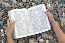 reading Bible over peebles