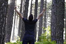 man with his hands raised in worship to God in a forest
