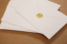 A stack of Christmas cards in envelopes with gold crown seal.