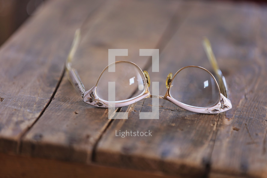 Cat eye glasses laying on a rugged wooden table.
