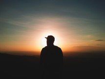 Silhouette of a man in a baseball cap at sunset.