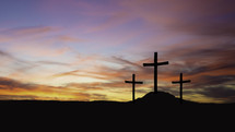three crosses on a hill at sunset