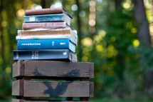 Stack of Bibles on a wooden crate outside.