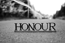 Letters spelling "honour" on the pavement.