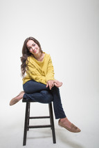 A brunette woman sitting on a stool 