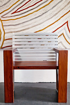 A modern wood chair against a painted striped wall