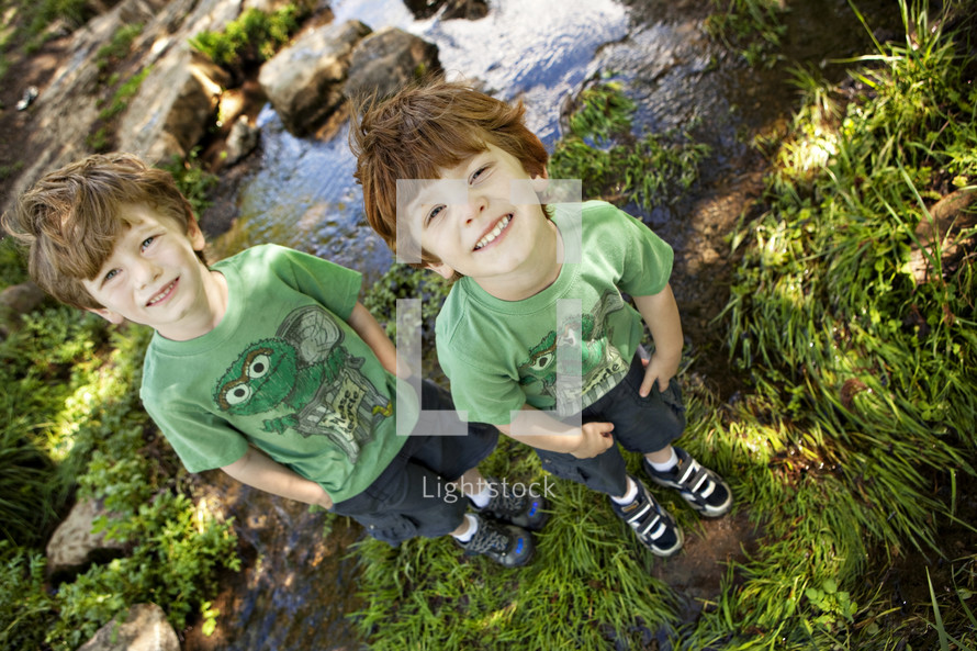 brothers standing in front of a stream