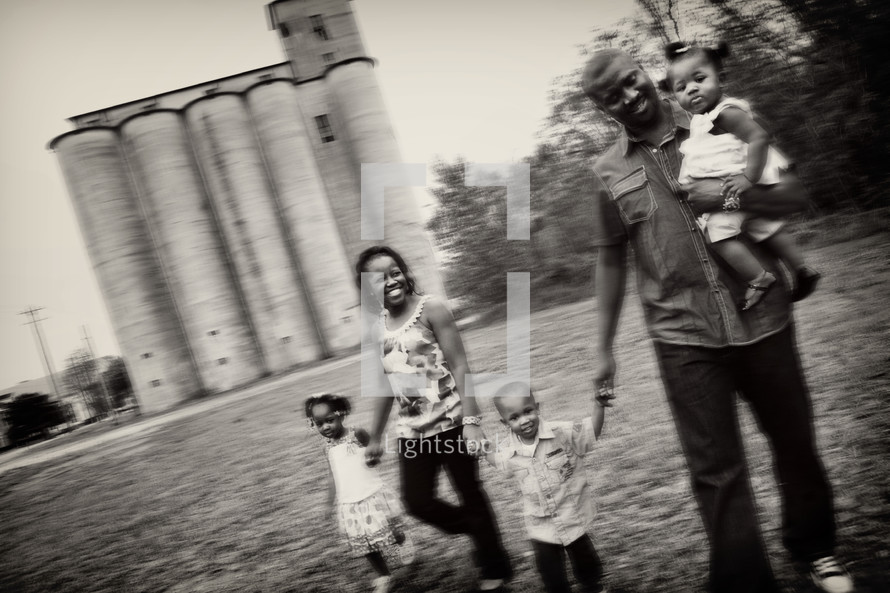 Family holding hands in front of a grain silo.