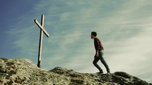 a man standing on a mountaintop in front of a cross