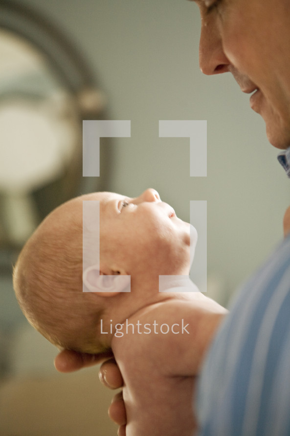 man holding and looking at a newborn
