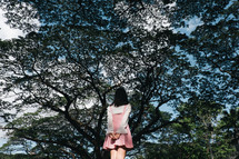 a girl standing in front of spring trees 