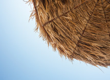 Thatched umbrella viewed from below with blue sky