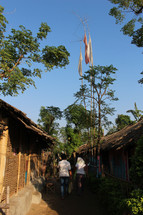 flags on trees above and alley between huts 