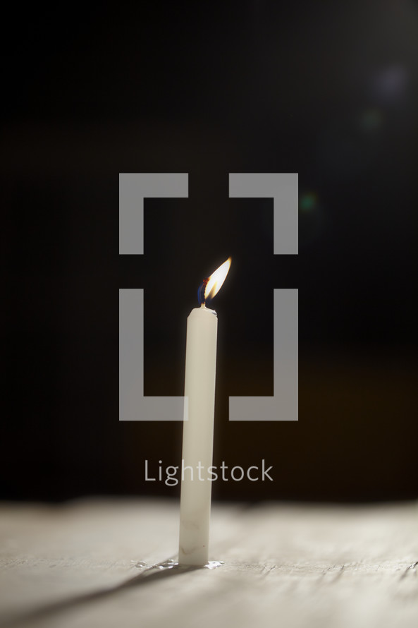 A single candle burns in the dark - lens flare 