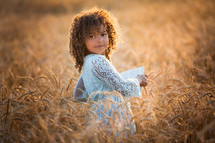 a little girl in a field of wheat 