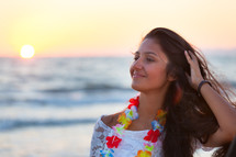 young teenager with a white dress on the beach at sunset.