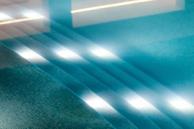 Bright underwater lights illuminating the turquoise tiles at the bottom of a swimming pool