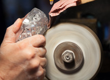 Close up of hands of the craftsman during sanding of a crystal ashtrays