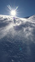 Wind blowing snow downhill in winter alpine mountains in sunny windy day vertical video
