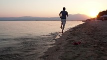 Man running along a beach at sunset