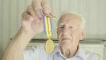 Senior caucasian man looking at an old medal themes of retired memories respect honour