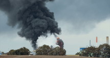 Accident in oil refinery - huge explosions and fireballs rising as thick black smoke covers the sky.